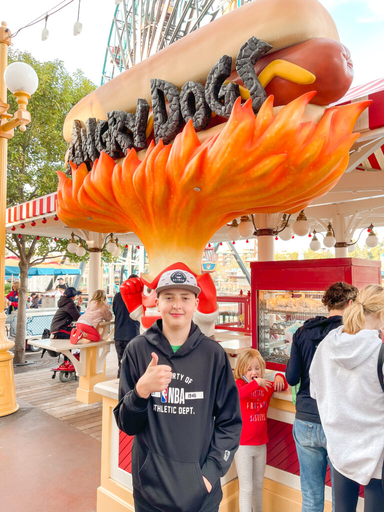 A boy in front of Angry Dogs hot dog stand at Disneyland.