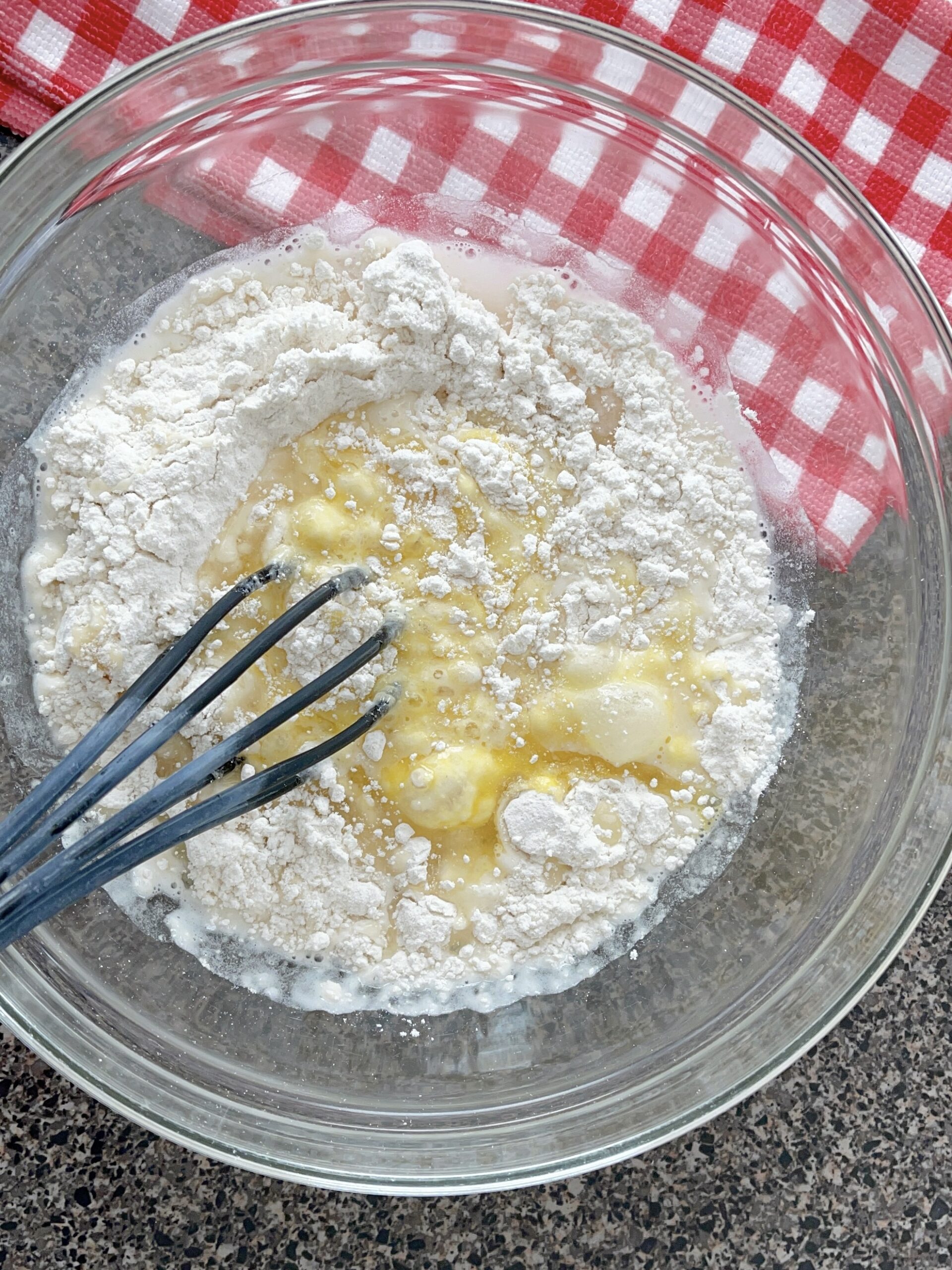 Pancake mix, egg, water, and oil in a bowl with a whisk to make waffles.