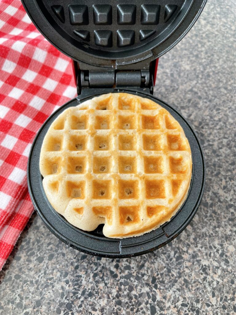 A pancake mix waffle in a waffle iron.