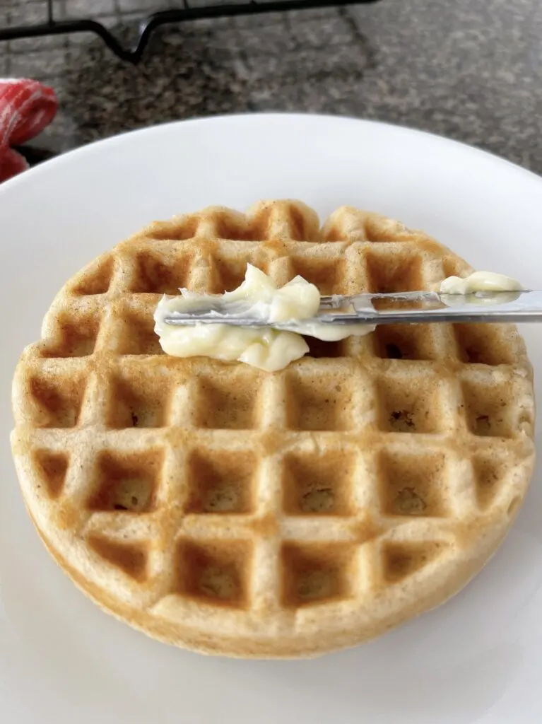 Butter being spread on a waffle.