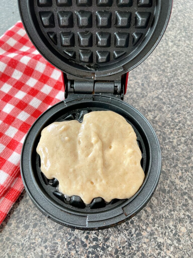 Waffle batter made with pancake mix in a red Dash waffle iron.