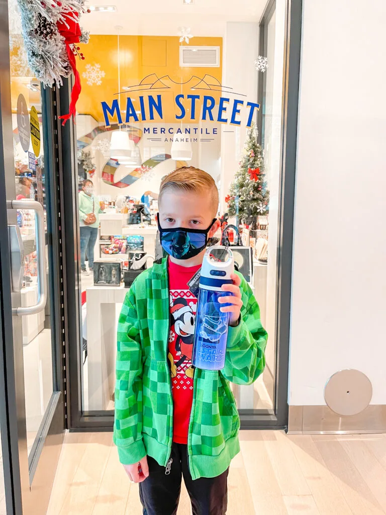 A boy with a Star Wars water bottle outside a gift shop.