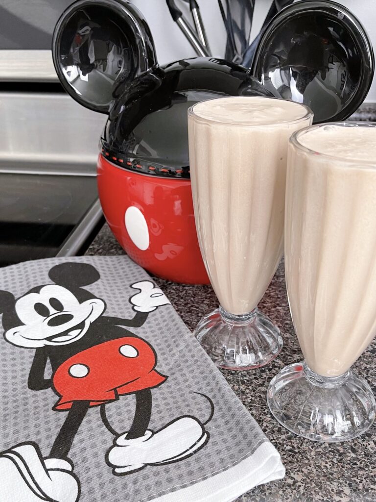 Two chocolate malts with a Mickey Mouse kitchen towel.