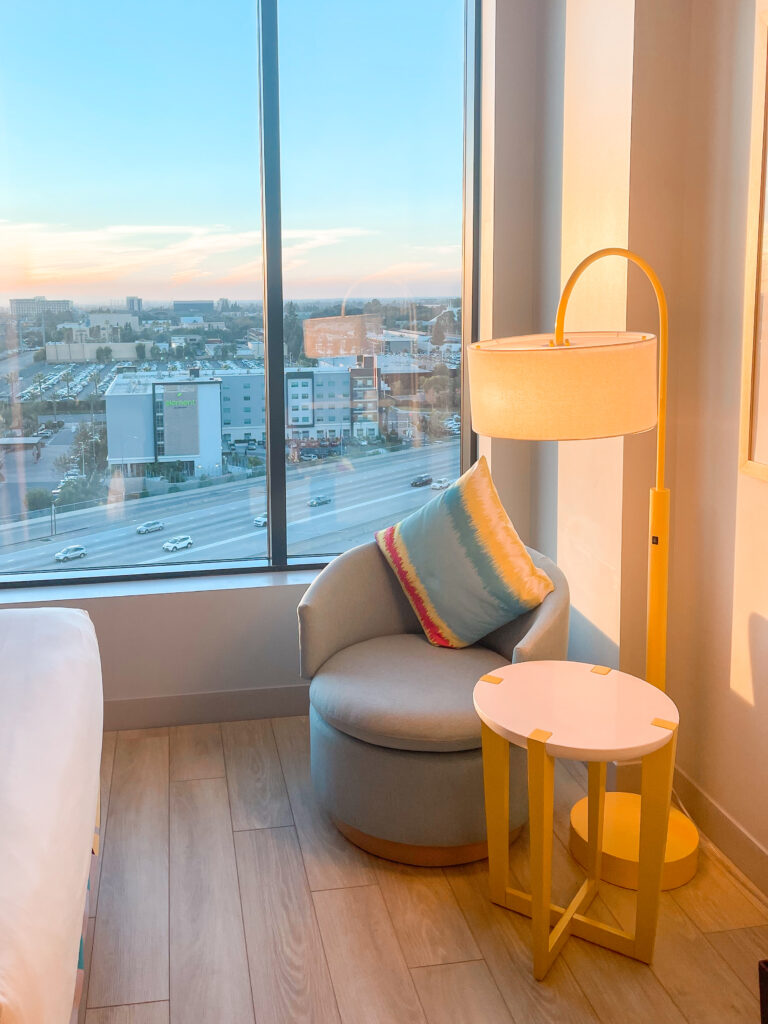 Chair, small table and lamp by the window with a view of Disneyland at Radisson Blu Anaheim.