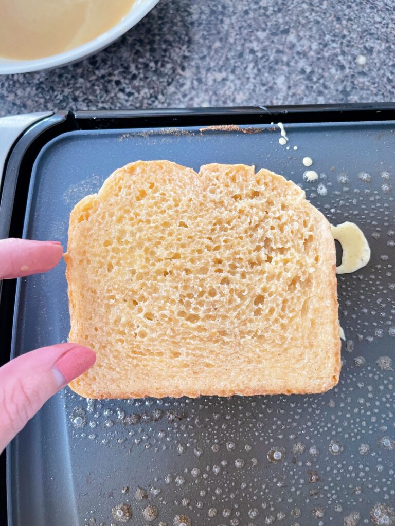 A slice of French Toast about to cooked on a griddle.