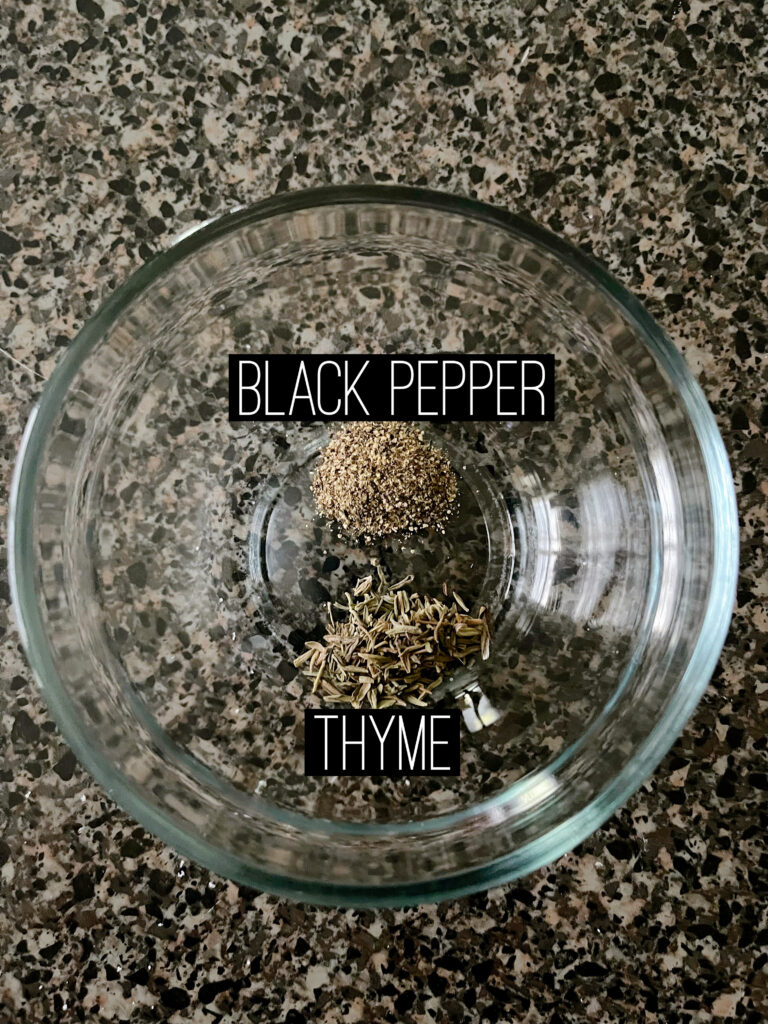 A bowl of black pepper and thyme to make garlic parmesan sauce.