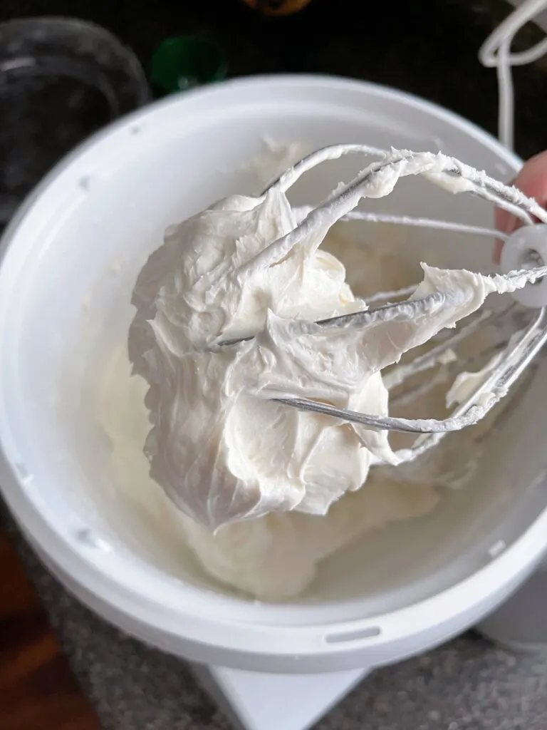 Vanilla buttercream frosting on a whisk.