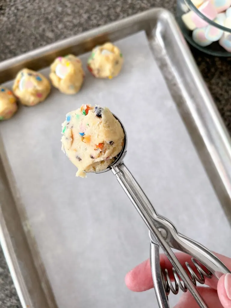 Rainbow chip cookie dough in a cookie scoop.