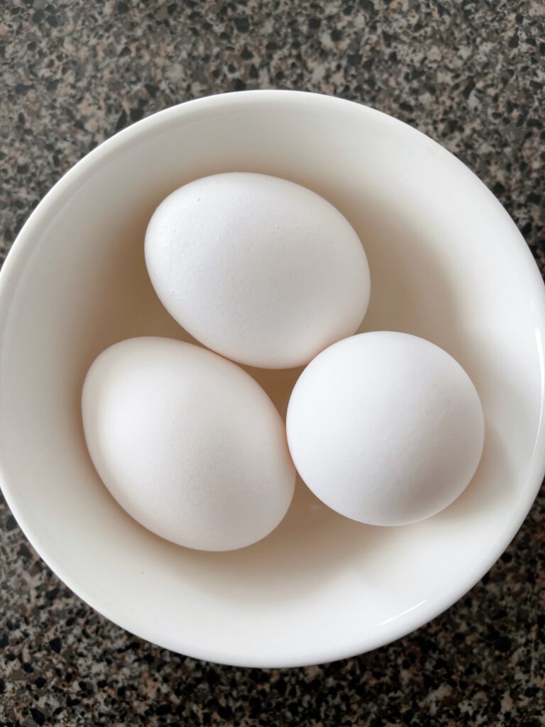 Three eggs in a white bowl.