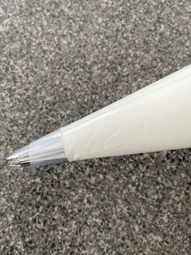 Vanilla buttercream frosting in a piping bag with a star tip.