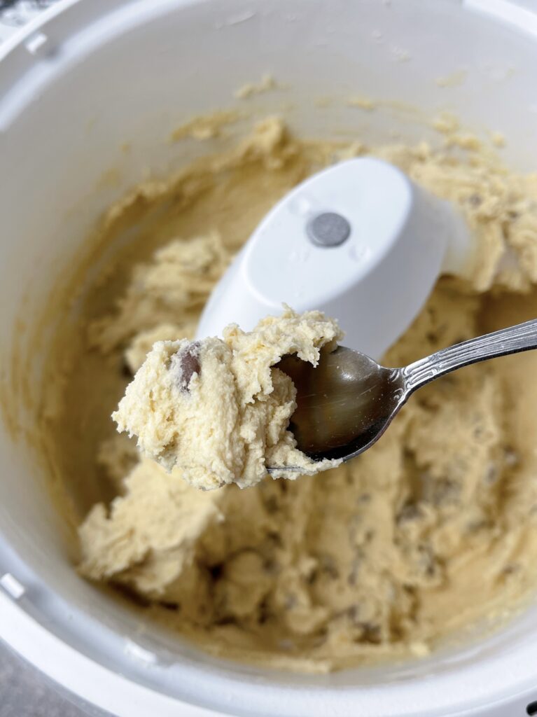 A spoonful of cookie dough and stand mixer.