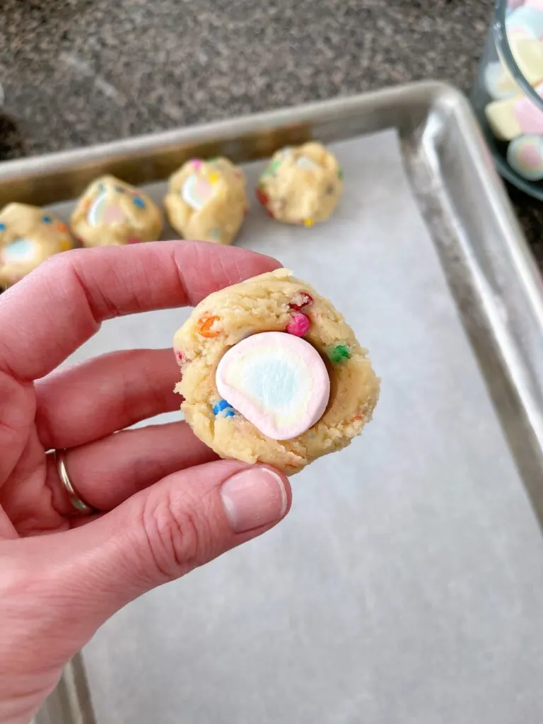 A marshmallow inside a ball of rainbow chip cookie dough.