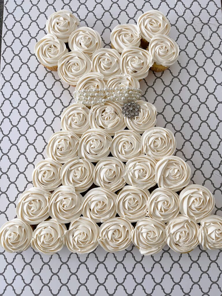 A pull apart cupcake cake shaped like a white dress.