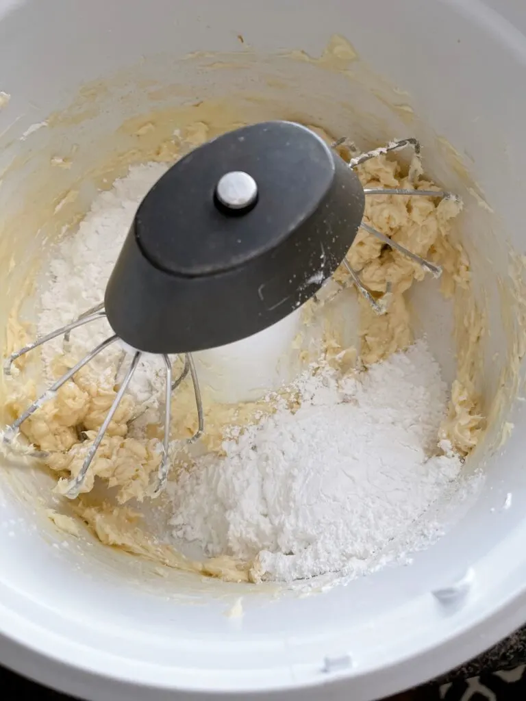 Powdered sugar and butter in a mixing bowl to make buttercream frosting.