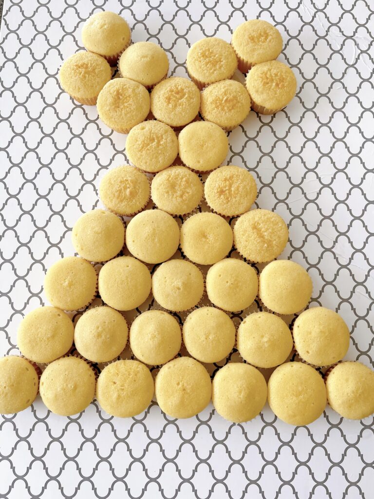 Thirty six cupcakes on a cake board arranged to look like a dress.