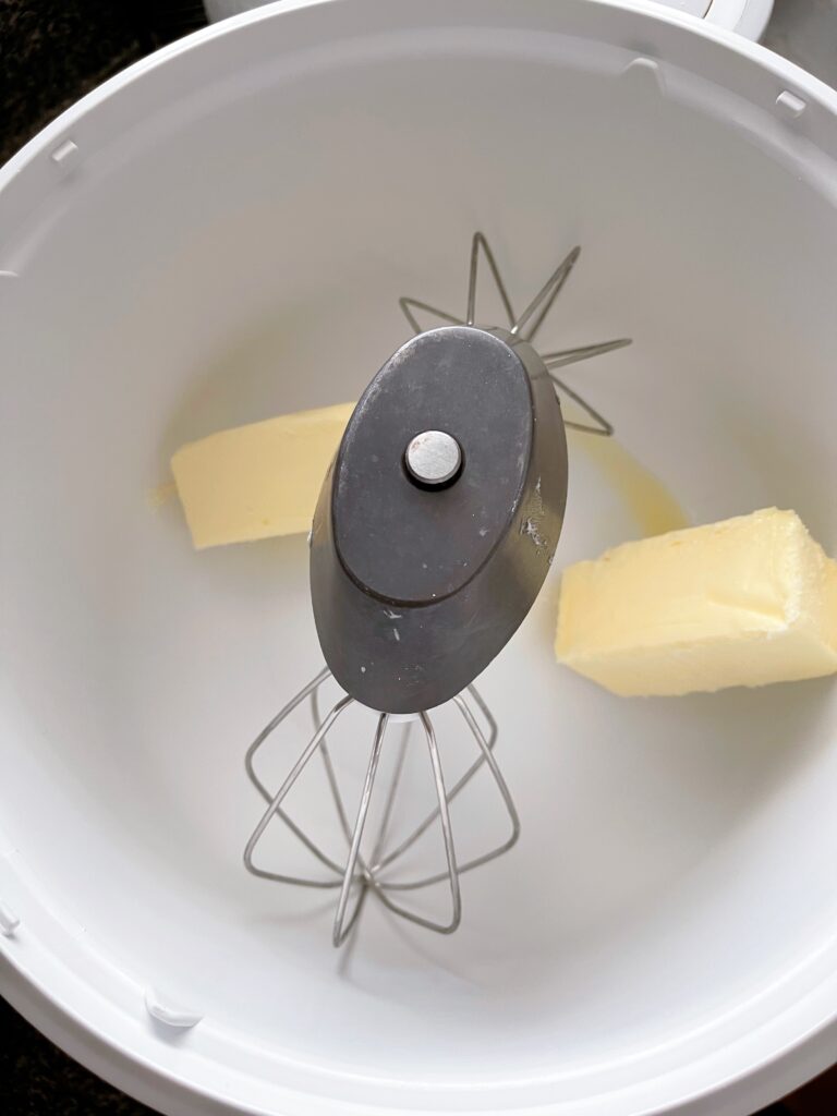 Two sticks of softened butter in a mixing bowl.