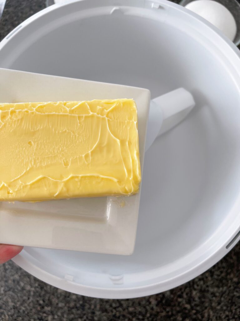Softened butter on a plate over a mixing bowl.