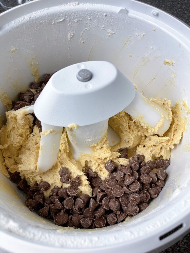 Chocolate chips in a mixing bowl with cookie dough.