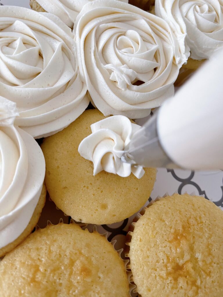 Vanilla buttercream frosting being piped onto a cupcake.