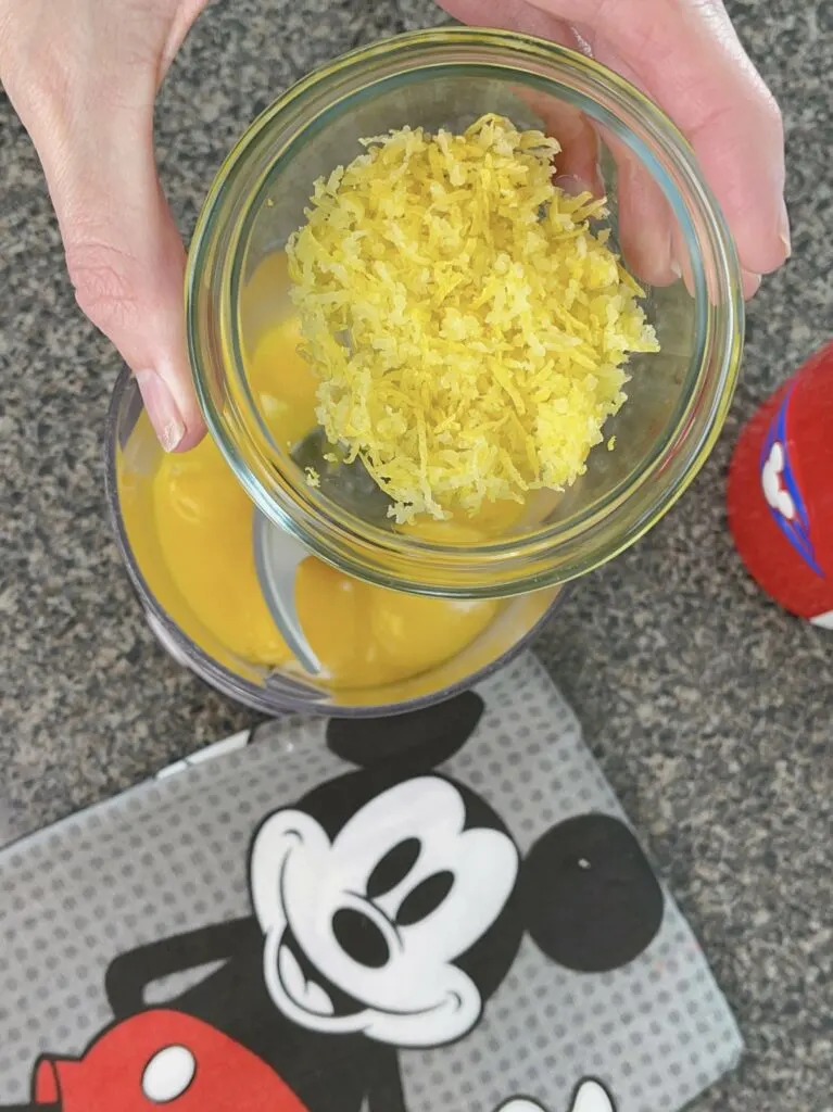 Lemon zest in a bowl and egg yolks in a food processor to make lemon icebox pie.