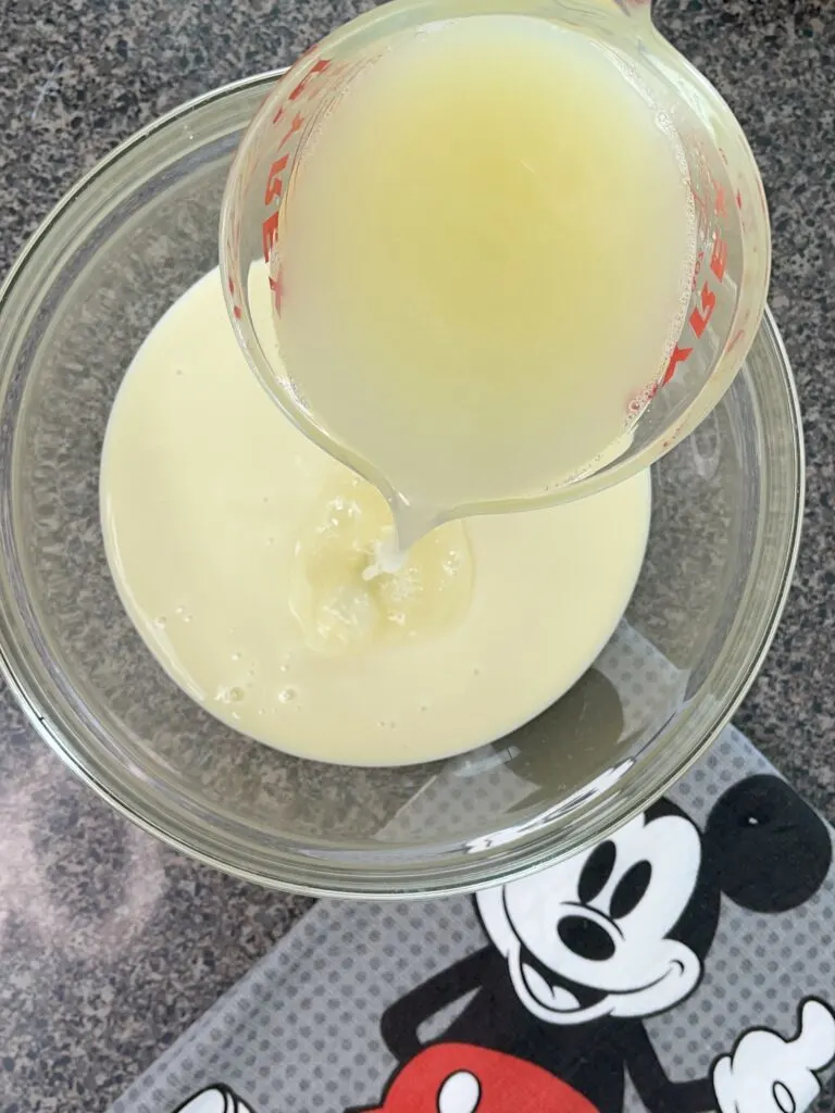 Lemon juice and sweetened condensed milk in a bowl to make lemon pie filling.