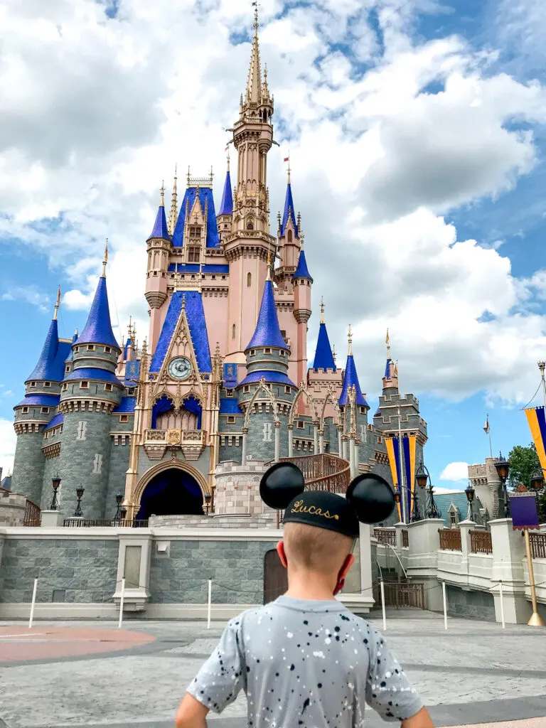 A boy in a Mickey Mouse hat in front of Cinderella Castle at Magic Kingdom.