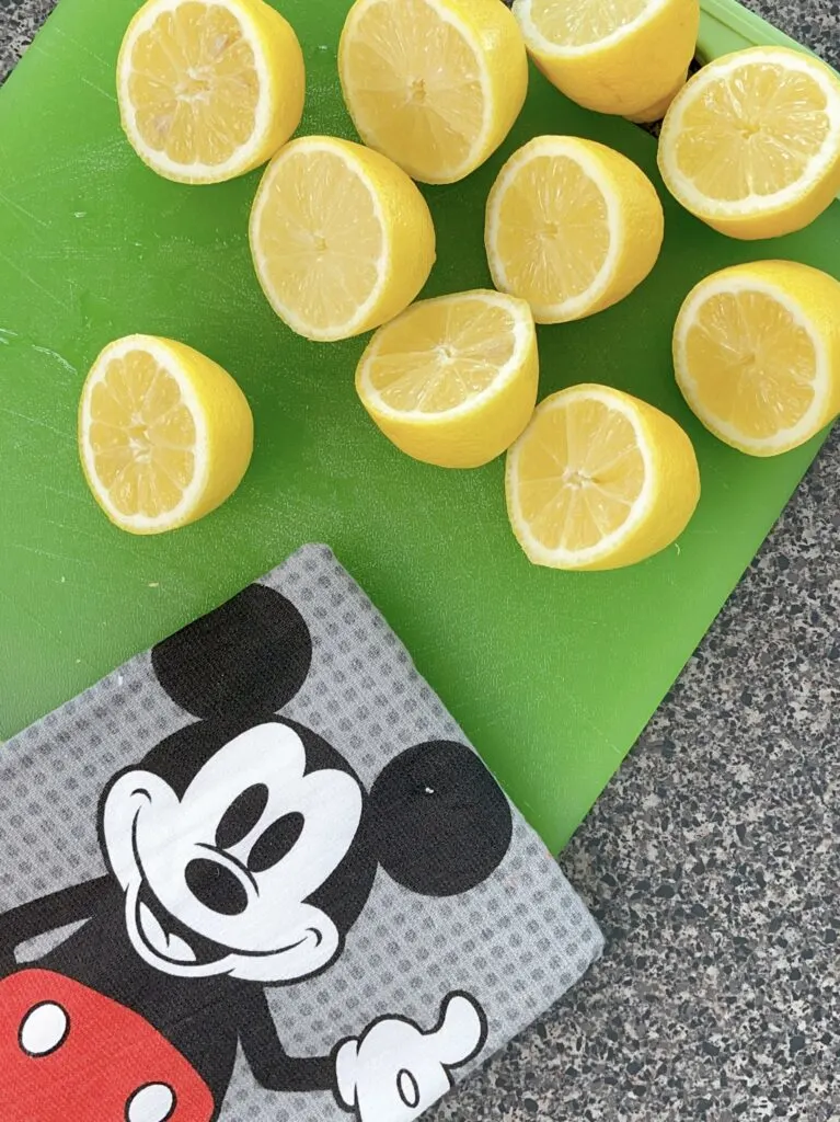 Lemons cut in half on a green cutting board and a Mickey Mouse towel.