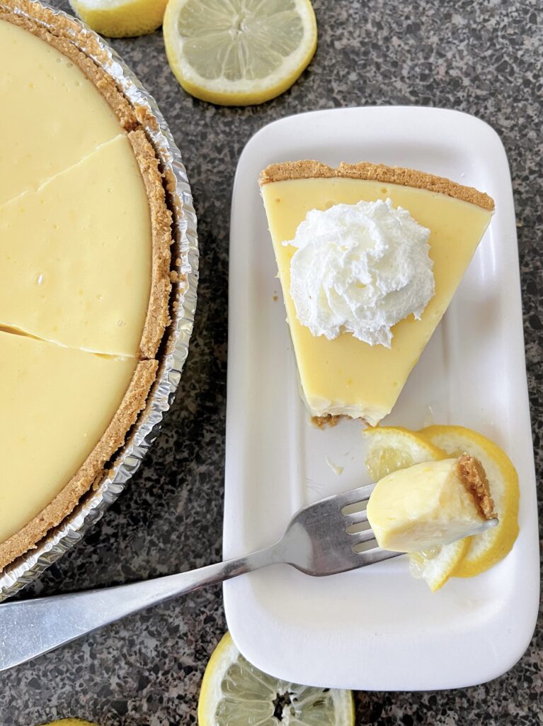 A slice of lemon icebox pie next to the full pie.