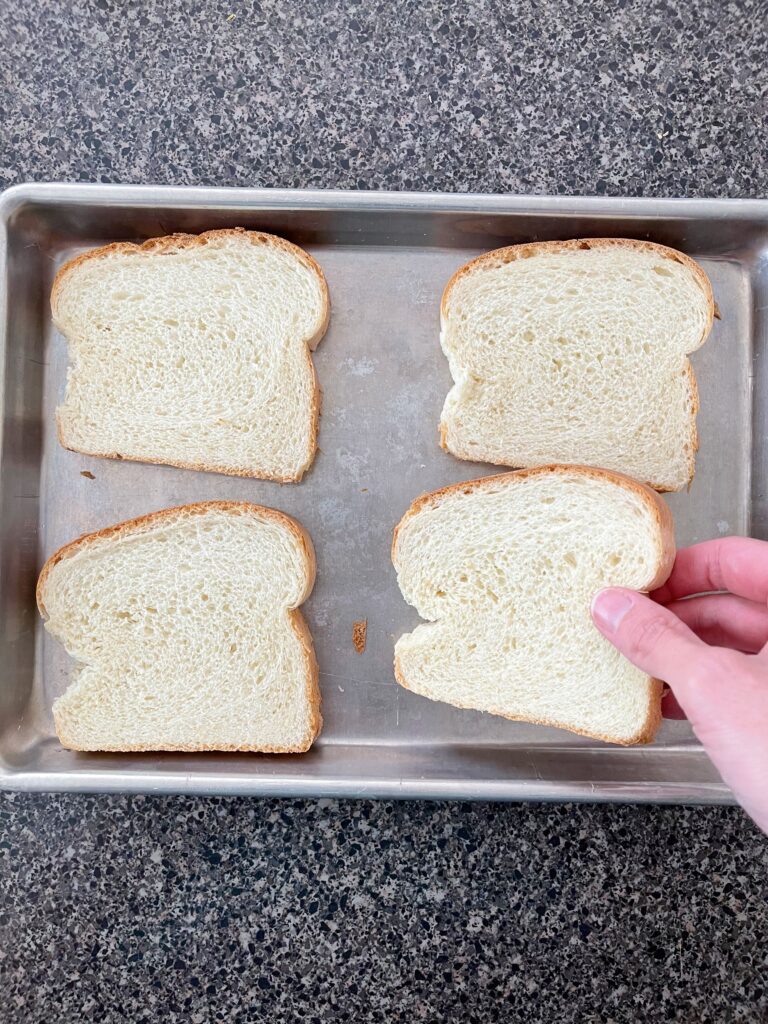 Four slices of bread on a baking sheet.
