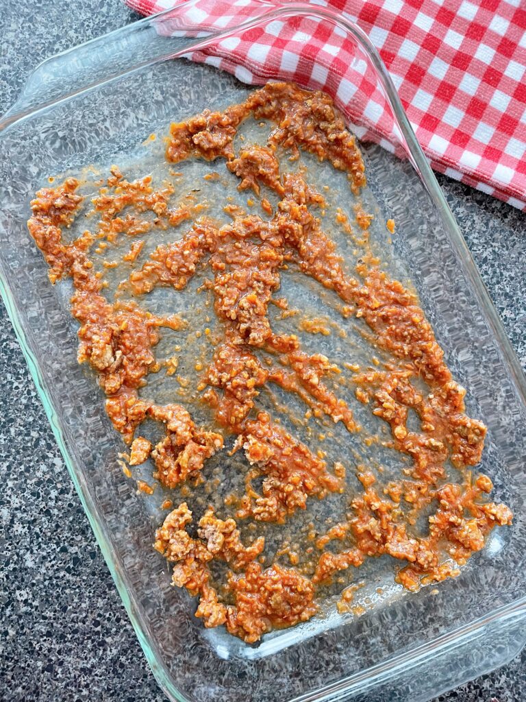 Spaghetti sauce on the bottom of a baking dish.