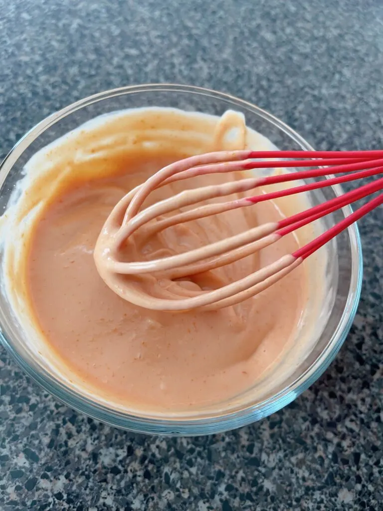A bowl of fry sauce with a whisk.