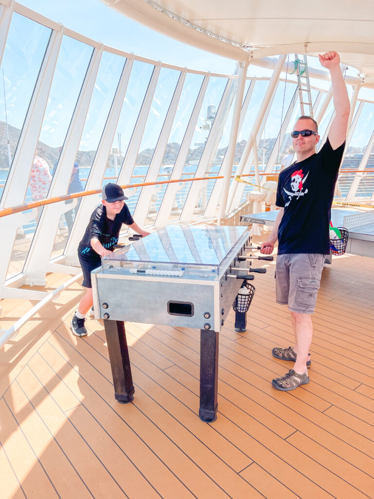 A dad and a child playing foosball on the Disney Wonder.