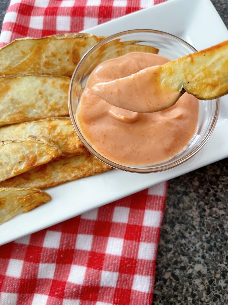 A potato wedge dipped in fry sauce.