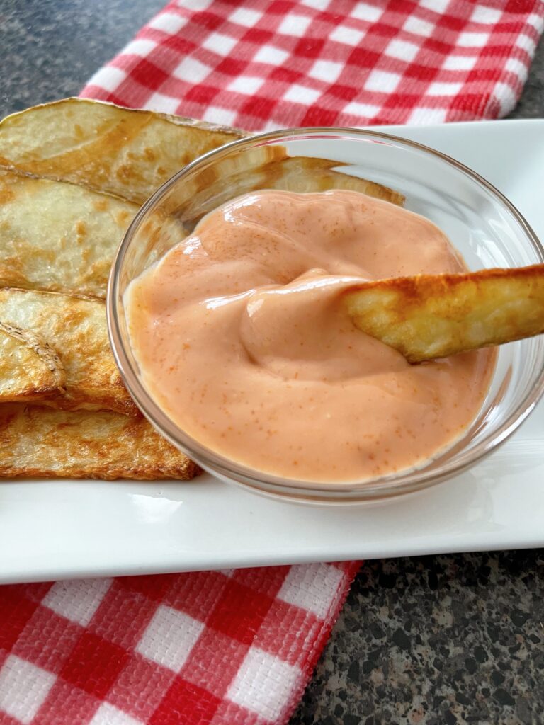 An air fried potato wedge with fry dipping sauce.