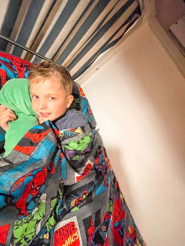 A child on a Disney Cruise bunk bed with Marvel sheets.