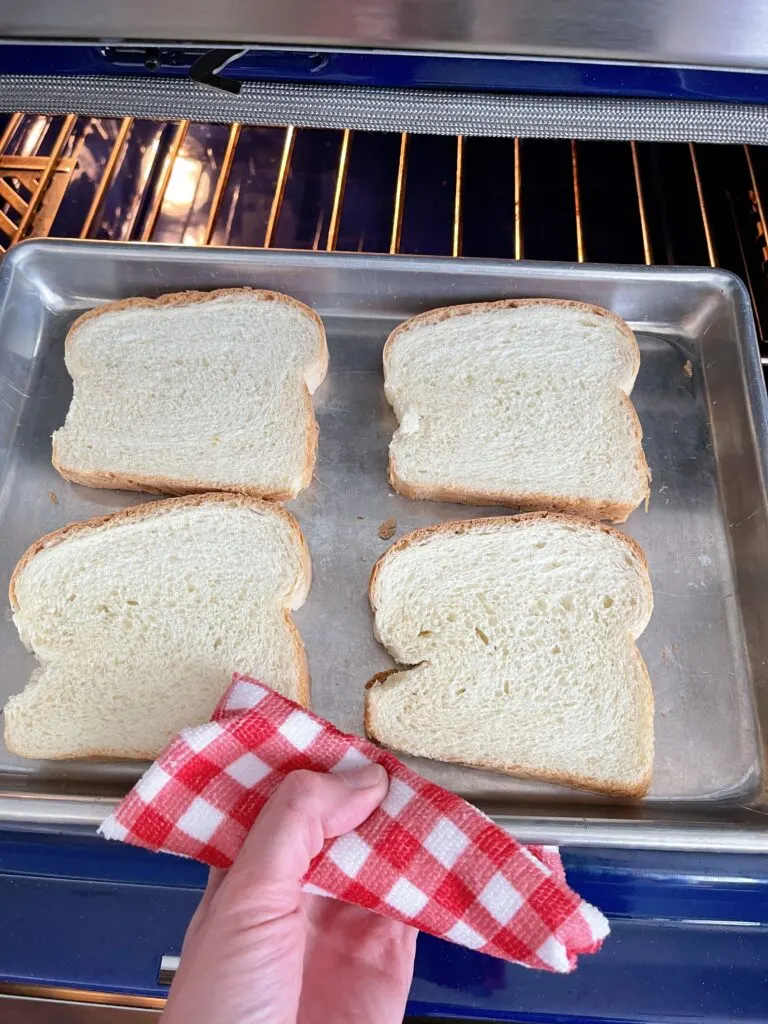 Four slices of bread on a baking sheet to be toasted in the oven.