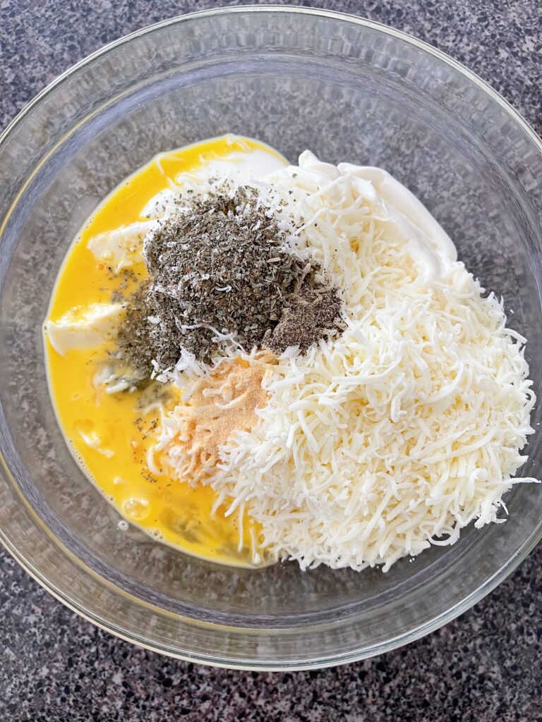 Ingredients for the ricotta mixture for lasagna in a mixing bowl.