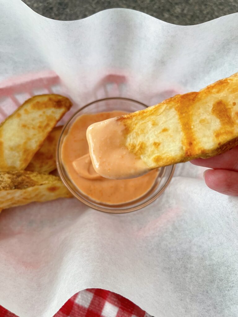 A potato wedge covered in fry dipping sauce.