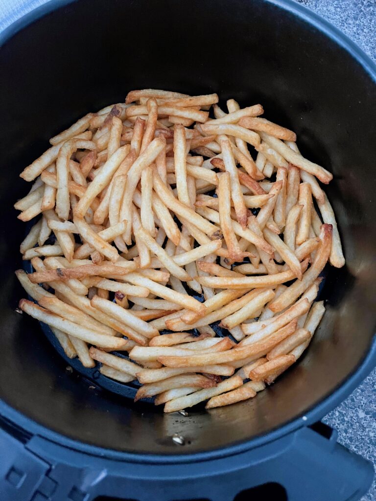 Frozen fries in an air fryer basket.