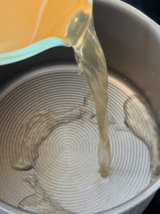 Broth being poured into a sauce pan.