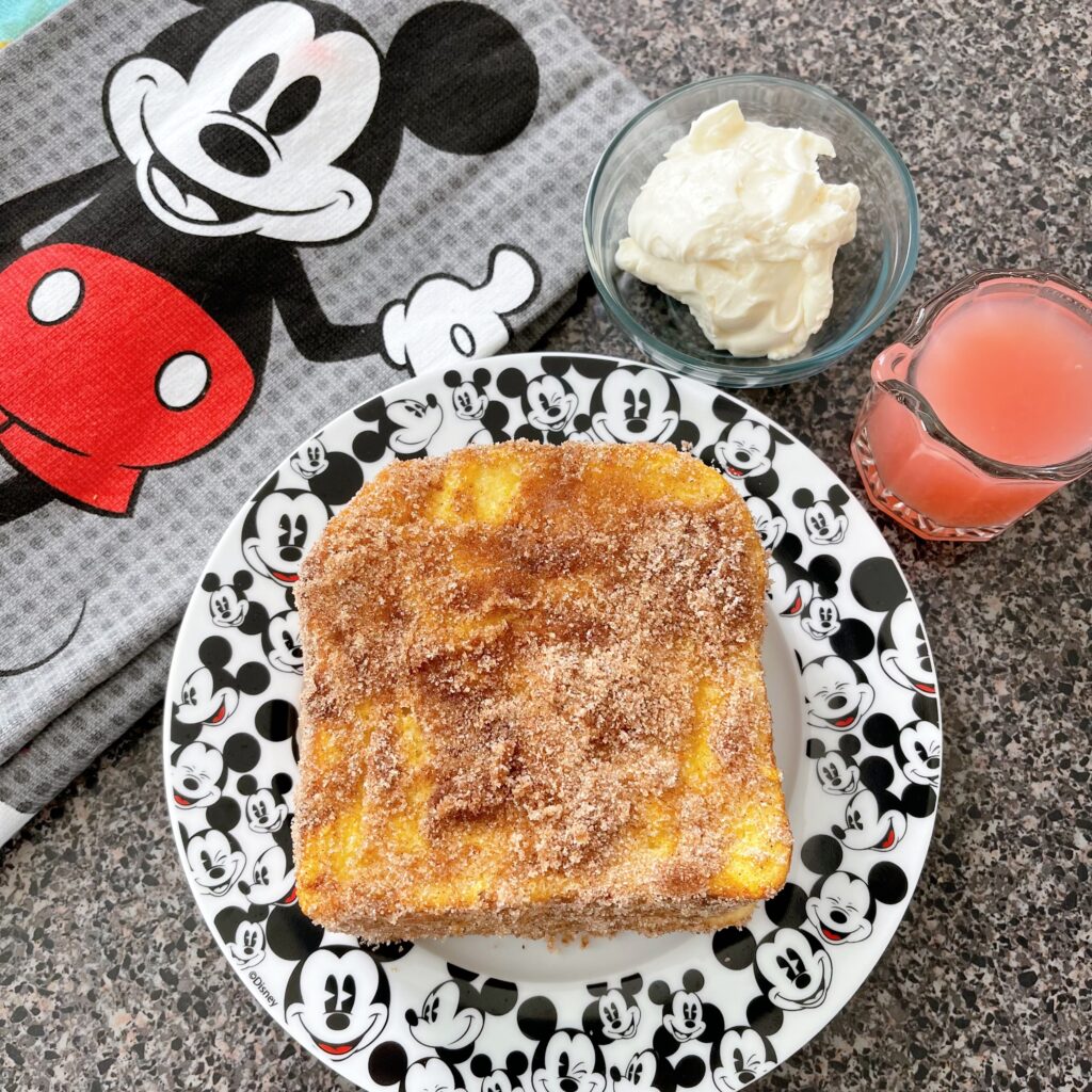 Crispy French Toast on a Mickey Mouse plate with guava syrup and whipped cream.