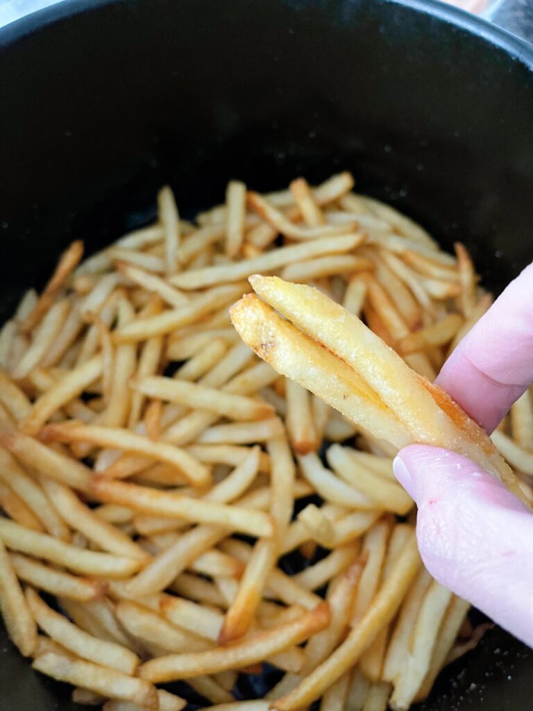 Frozen fries in an air fryer basket.