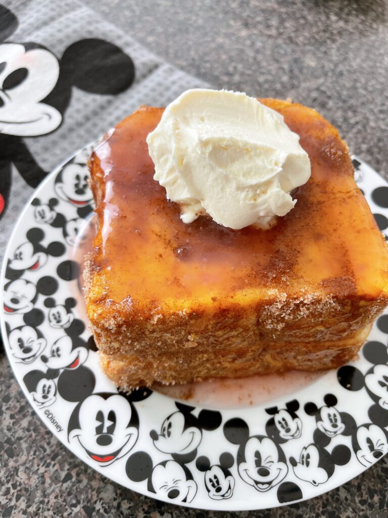 Disneyland stuffed French toast on a plate with guava syrup and whipped cream.