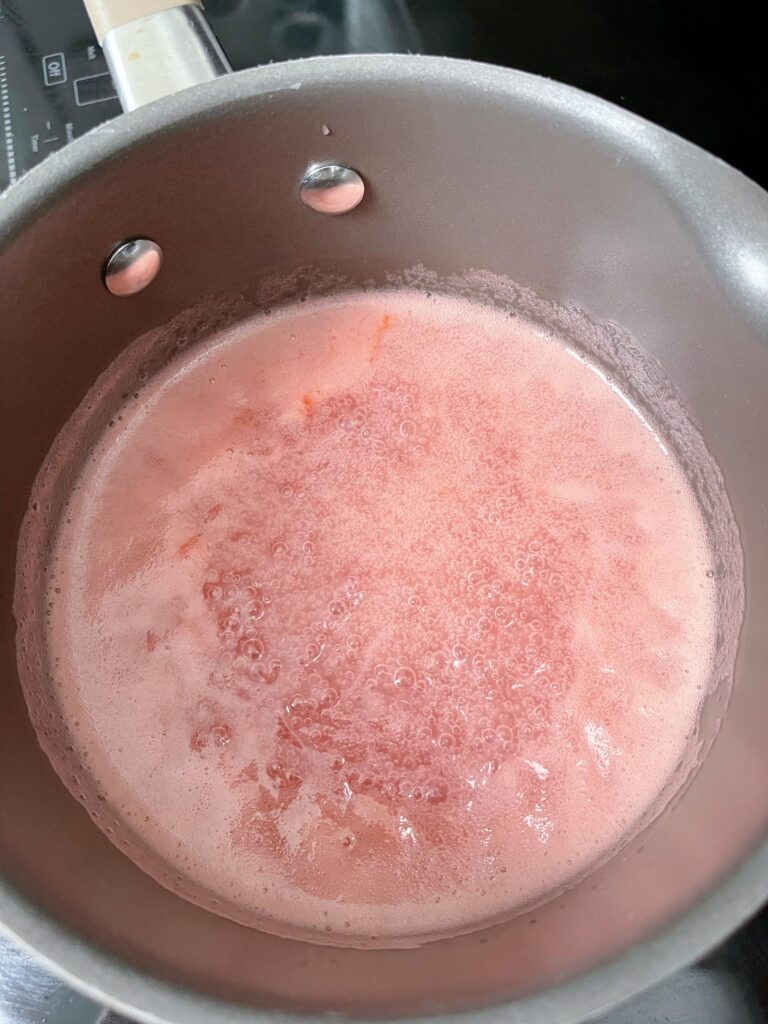 Guava syrup in a pan on a stove.