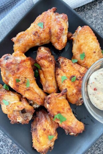 Air fryer chicken wings on a black plate.