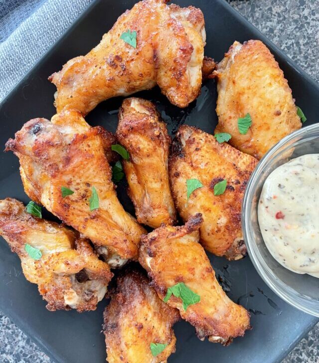 Air fryer chicken wings on a black plate.