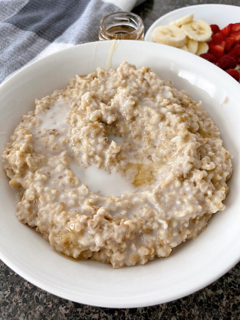 A bowl of steel cut oatmeal with milk and honey.