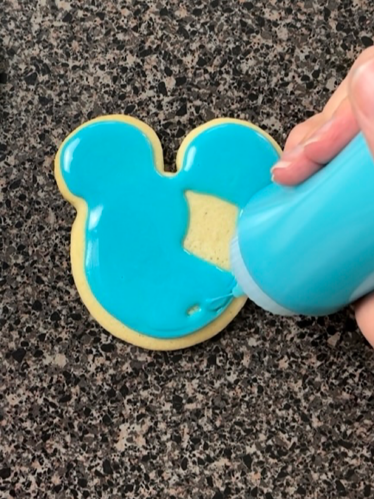 A cookie being iced with icing that hardens.