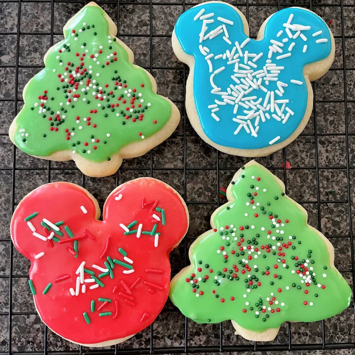 Four sugar cookies decorated for Christmas with icing that hardens and sprinkles.