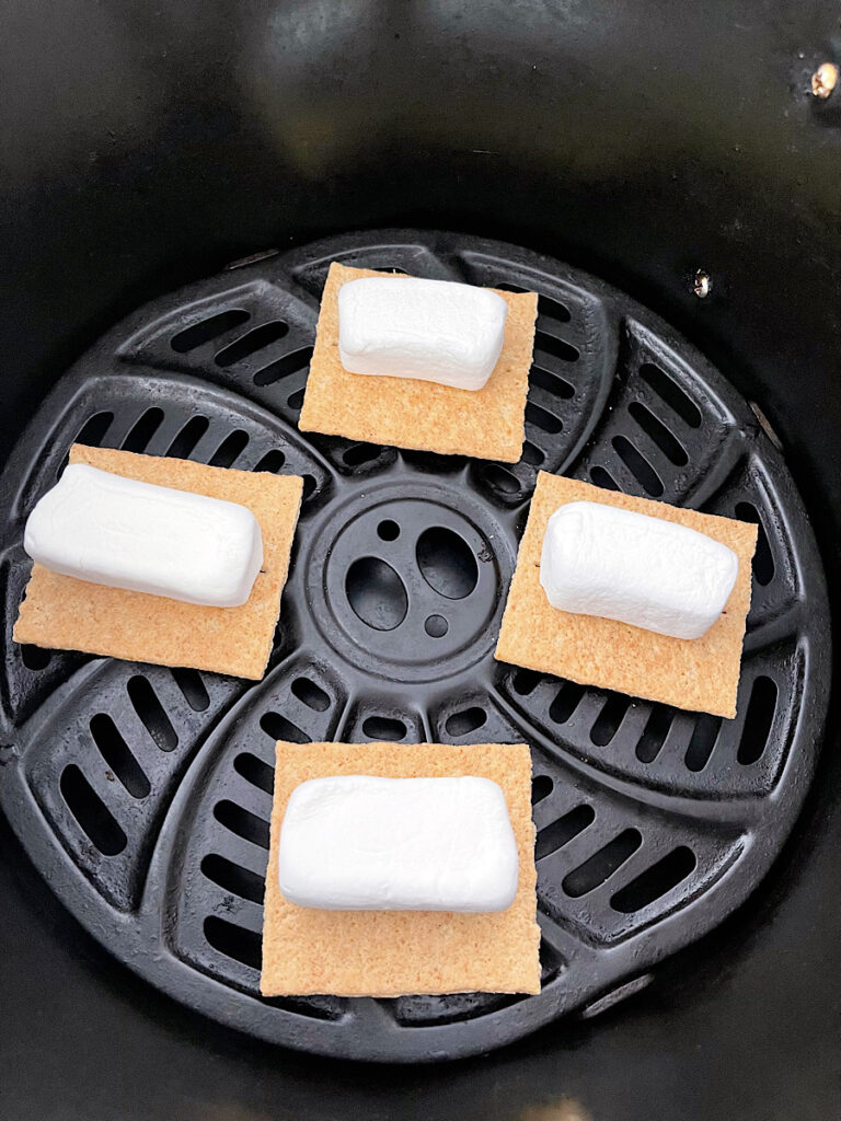 Marshmallows on top of graham crackers in an air fryer.